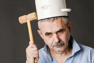 A crazy man with a saucepan on his head tries to find a thought with a hammer. - obrazy, fototapety, plakaty