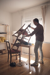 Man working in a small home workshop for furniture repairing and restoration.