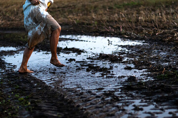 Muddy bare feet of a running woman running across field