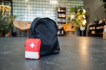 A first-aid kit is on the floor along with a backpack, travel medicines, and a black bag.