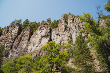 Rocky riverbank, orange rocks, spring in nature, mountainous terrain, canyon with outcrops on top of the mountain.