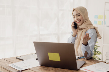Beautiful Asian Muslim businesswoman uses smartphone to view social media application Answer chats...
