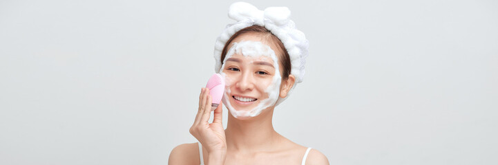 Panorama of asian female applying foamy cosmetic product on face during skincare routine