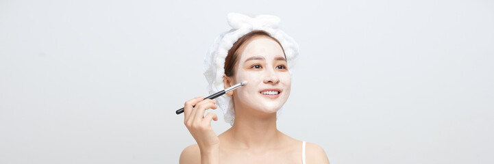 Banner of Beautiful woman having clay facial mask apply by beautician.