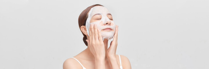 Banner of beautiful young woman applying rejuvenation facial mask on her face - 698461275