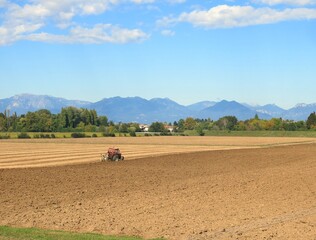 Obraz premium tractor in the middle of the plow field during the sowing period in the Po Valley in Italy
