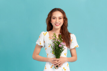 Young beautiful girl with long hair and hat posing with a bouquet of wildflowers.