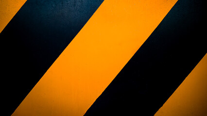 Background image, texture, steel wall painted in yellow and black at diagonal angles that is distinctive and is a symbol of an industrial factory.