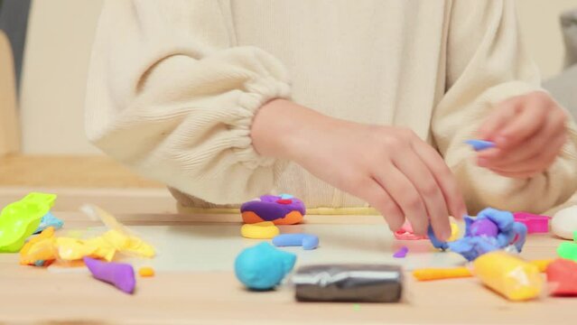 Modern educational play. Creative molding developing. Creative clay playdate. Fun with educational toys. Unrecognizable little girl playing with colorful pieces of plasticine