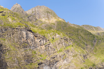 The barren rocky mountains in the middle of the countryside , Europe, France, Occitanie, Hautes-Pyrenees, in summer on a sunny day.