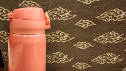 Thermos bottle on the background of a fabric. Close-up - obrazy, fototapety, plakaty
