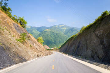 An asphalt road in the middle of the countryside and mountains, in Asia, Vietnam, Tonkin, between Dien Bien Phu and Lai Chau, in summer, on a sunny day.