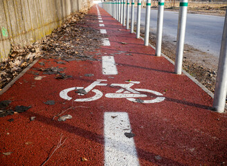 Red painted bicycle lane with small aluminium pilons near a small romanian city.