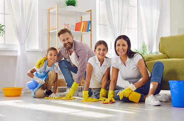 Happy family having spring cleaning day. Adults and little ones washing floor at home all together....