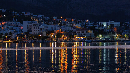 Night view of Bodrum city. Famous tourist city in evening lights, calm water of Bodrum bay. Turkey (Turkiye)