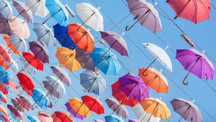 Fototapeta na wymiar Multicolored umbrellas hanging above street in Antalya in sunny day and blue sky. Turkey (Turkiye)