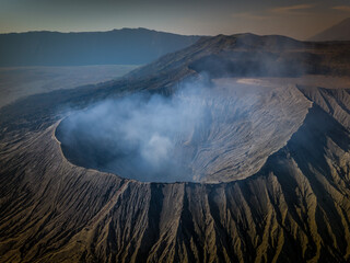 Aerial landscape view of the Bromo volcano crater with smoke coming. An active volcano in Tengger Semeru National Park in East Java, Indonesia.