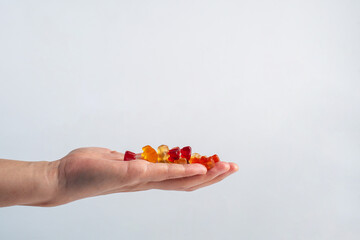 Hand and colorful Fruity Gummy Worm Candy on white background.