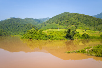 The red river in the middle of the green mountains, in Asia, Vietnam, Tonkin, between Dien Bien Phu and Lai Chau, in summer, on a sunny day.