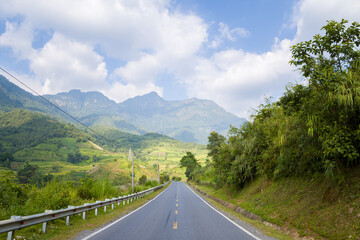 An asphalt road in the middle of the countryside and mountains, in Asia, Vietnam, Tonkin, between Lai Chau and Sapa, in summer, on a sunny day.