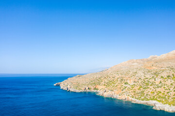 Fototapeta na wymiar The arid rocky coast and its green countryside along small beaches, in Europe, Greece, Crete, towards Preveli, At the edge of the Mediterranean Sea, in summer, on a sunny day.