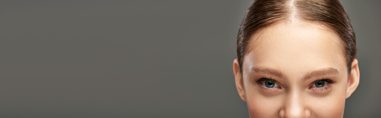 cropped banner of young woman with blue eyes and perfect skin looking at camera on grey background