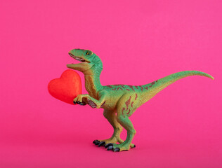 Green cute dinosaur with red heart on  pink background. Creative minimal greeting card on Valentines day. Love concept.