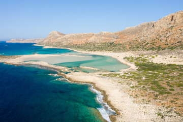 The sandy beach with pink reflections at the foot of the rocky cliffs, in Europe, Greece, Crete, Balos, By the Mediterranean Sea, in summer, on a sunny day.