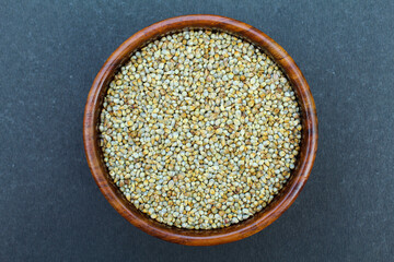 Organic Pearl millet or bajra in a wooden bowl on black background