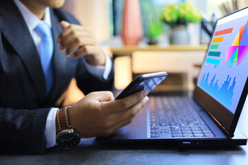 Businessman holding smartphone to connection or synchronization for transfer to laptop computer and...
