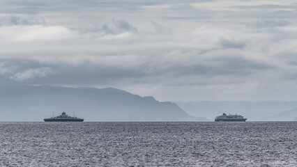 A ferry sailing on the Trondheim Fjord. Dramatic clouds before storm and mountains.