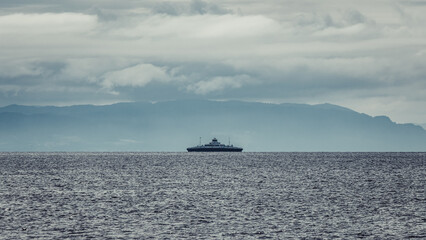 A ferry sailing on the Trondheim Fjord. Dramatic clouds before storm and mountains. - obrazy, fototapety, plakaty