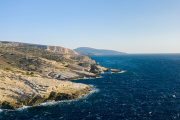 Obraz premium The arid rocky coast and its green countryside, in Europe, Greece, Crete, towards Matala, By the Mediterranean Sea, in summer, on a sunny day.