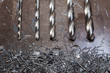 Drill bits for drilling steel lie on steel shavings close-up.