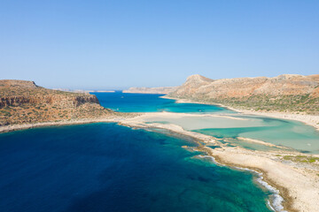 The sandy beach with pink reflections at the foot of the rocky cliffs, in Europe, Greece, Crete, Balos, By the Mediterranean Sea, in summer, on a sunny day.