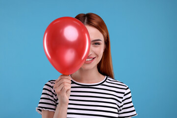 Happy woman with red balloon on light blue background