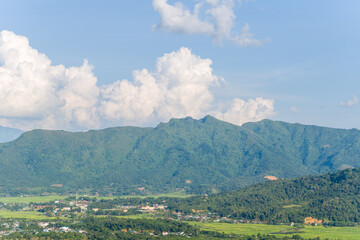 Fototapeta na wymiar A city in the valley among green rice fields and green mountains, Asia, Vietnam, Tonkin, between Son La and Dien Bien Phu, in summer on a sunny day.
