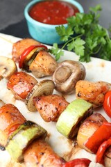 Delicious shish kebabs with mushroom, onion, tomato and zucchini on grey table, closeup