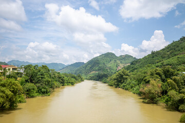 A river in the middle of mountains and green tropical forests, in Asia, in Vietnam, in Tonkin,...