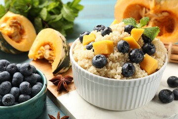 Tasty quinoa porridge with blueberries and pumpkin in bowl on table, closeup