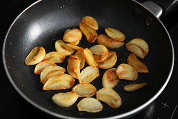 Frying pan with fried garlic cloves, closeup