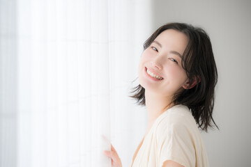 Young woman standing by the window, smiling for the camera