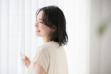 Fototapeta na wymiar 窓辺に佇む若い女性　笑顔の横顔
