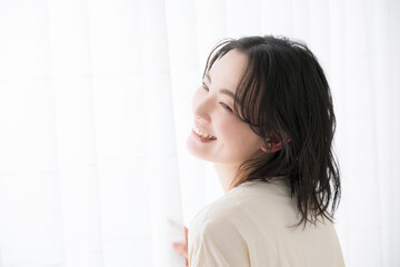 Young woman standing by the window, smiling profile