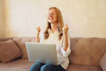Caucasian young woman working with laptop doing winner gesture celebrate clenching fists say yes...