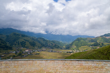 A view over the green and yellow rice fields, in Asia, Vietnam, Tonkin, Sapa, towards Lao Cai, in summer, on a cloudy day.