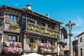 Cruz de piedra del siglo XVIII y hermosa arquitectura tradicional con balcones adornados con...