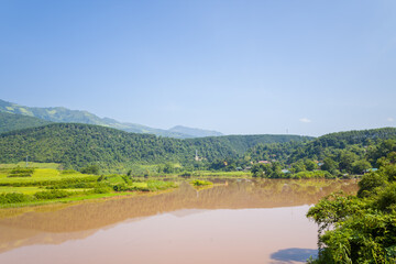 The red river in the middle of the green mountains, in Asia, Vietnam, Tonkin, between Dien Bien Phu and Lai Chau, in summer, on a sunny day.