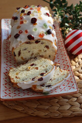 Sliced traditional german sweet bread with candied fruits called Stollen on a decorated plate on wooden table with festive Christmas decorations
