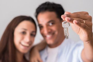 Close up of new home keys and young interracial couple smile and show the property - new life...